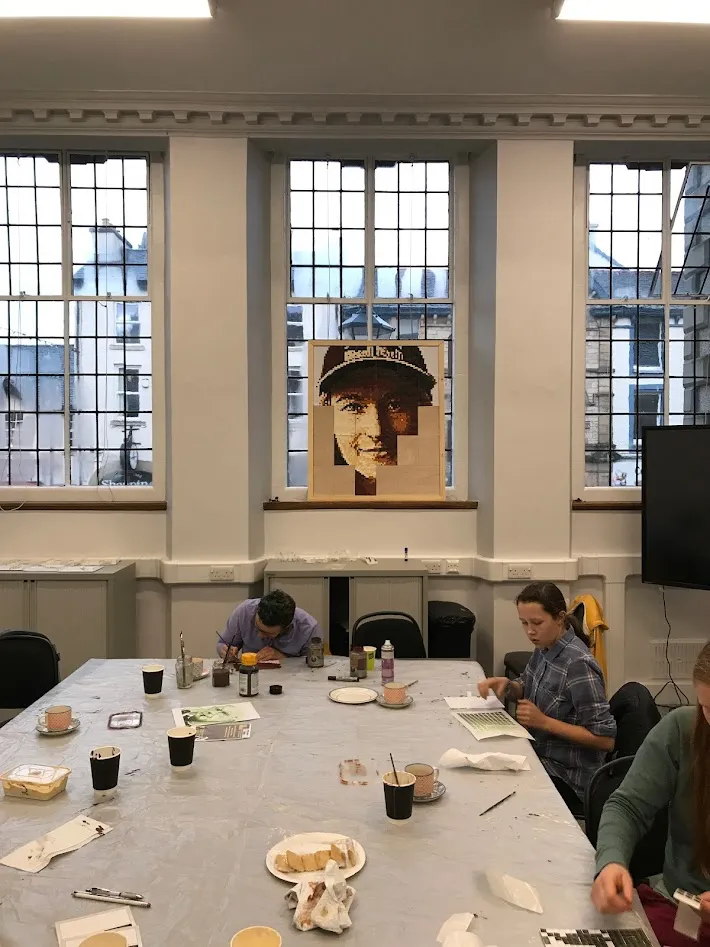 Room with three people and a picture at the end.