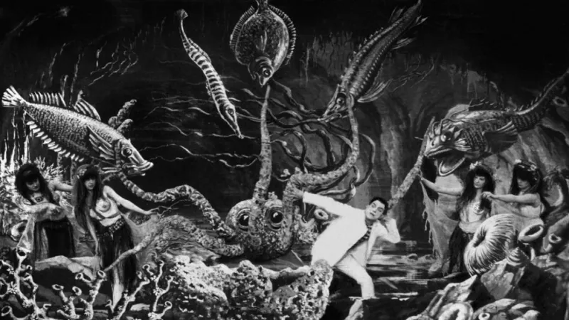 Actors - 2 mermaids on each side and a sailor in the middle with a giant octopus and fish all around