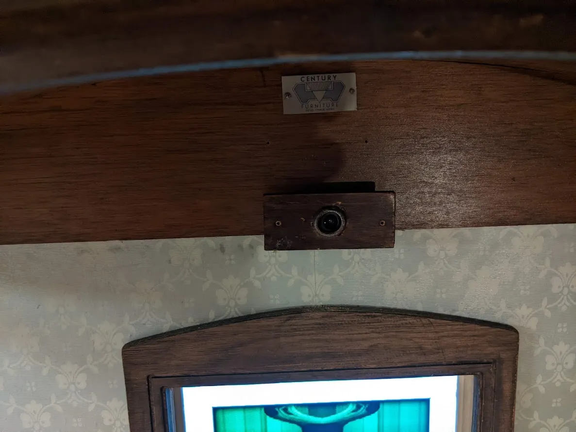 Webcam with wooden surround above a framed vertical
screen.