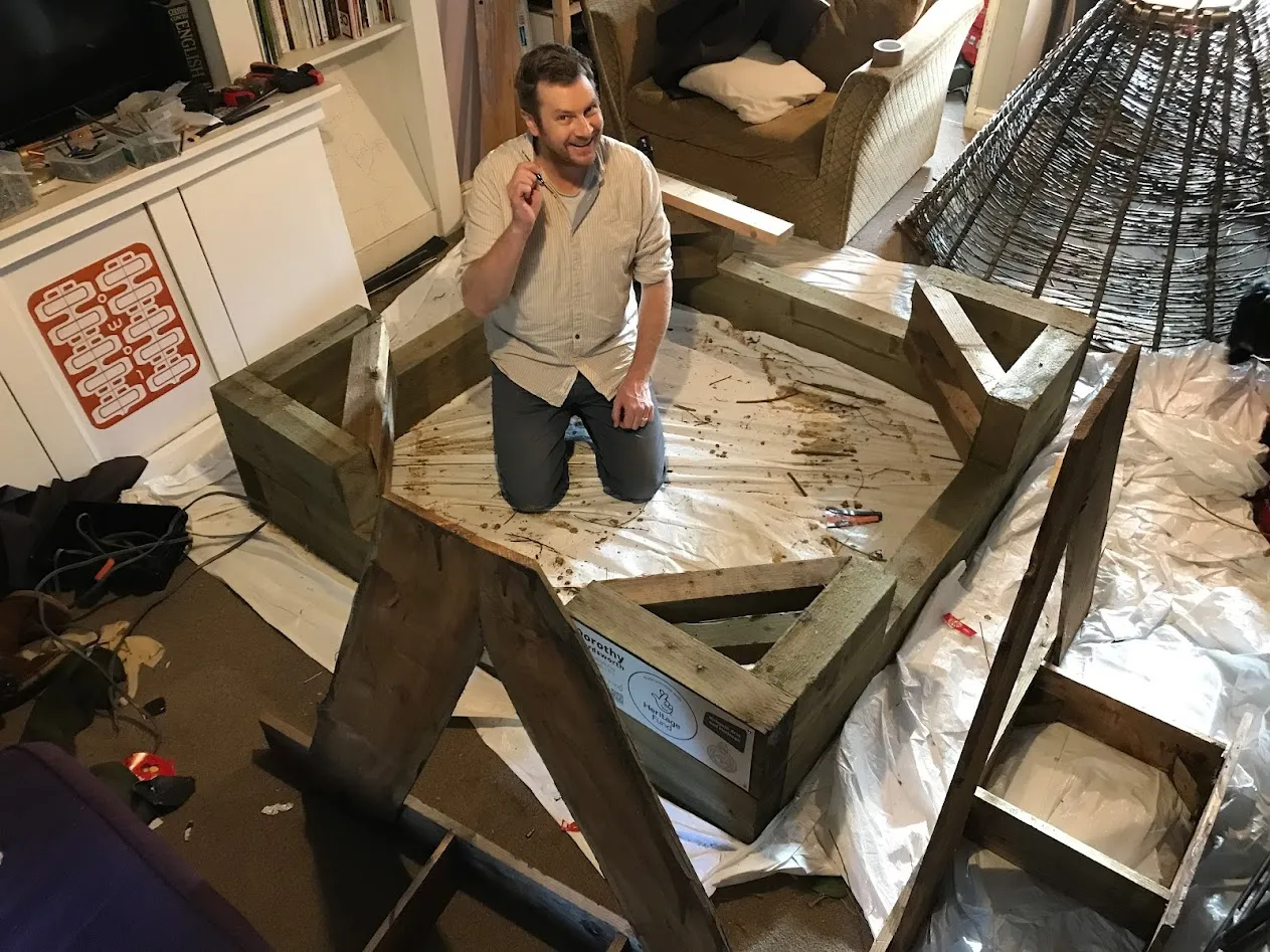 Man kneeling in framework of wood