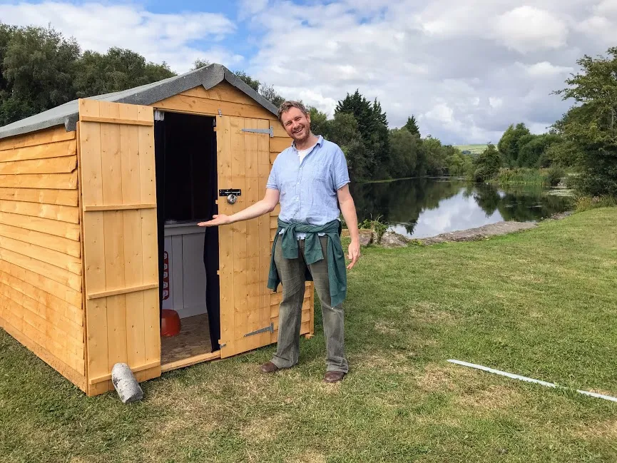 Man standing next to shed at the end of the canal