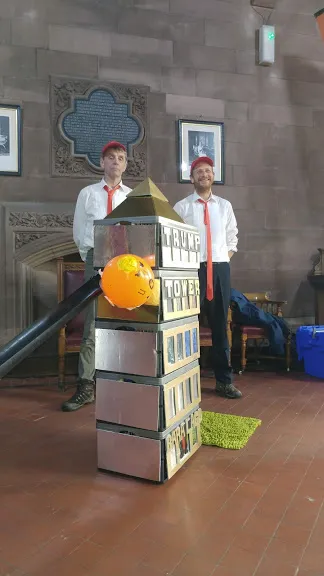 Two men standing behind golden tower.