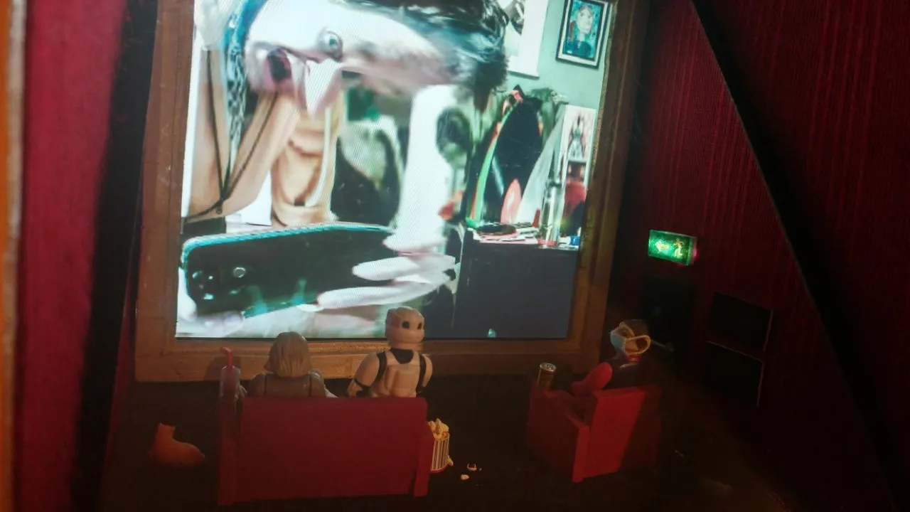 Distorted face on screen in box with action figures