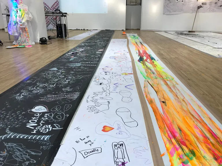 Three long sheets of painted paper on floor.