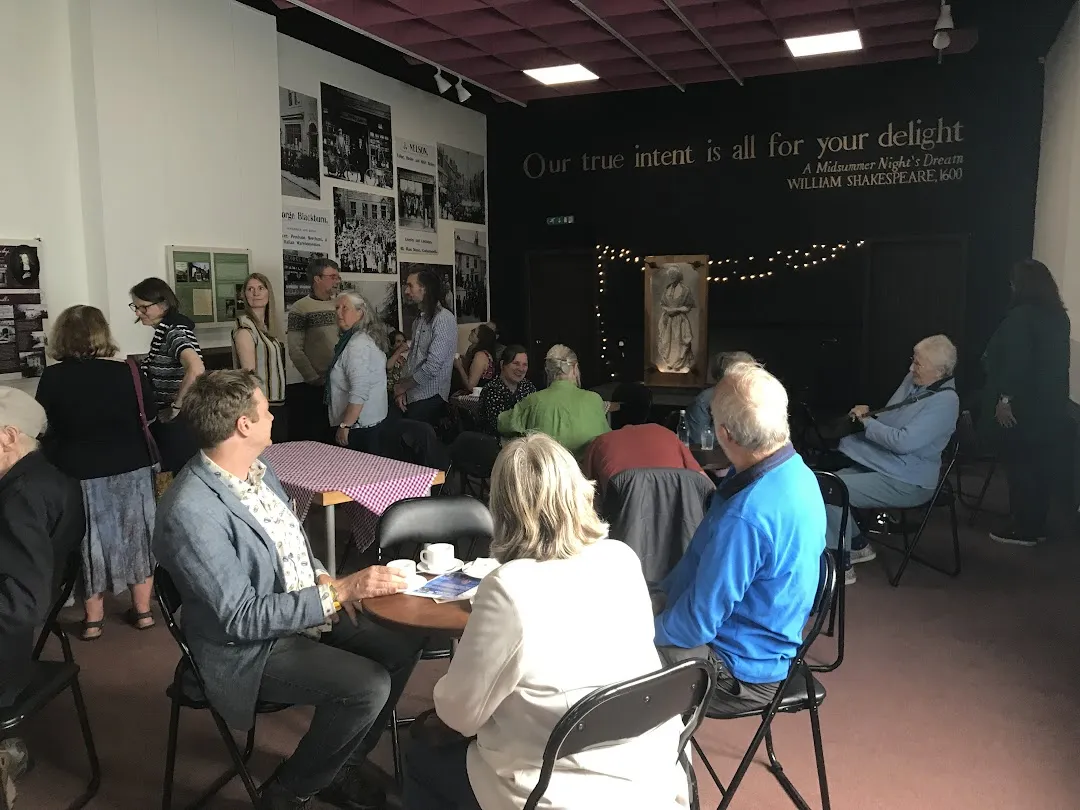 Group of people sitting around a table looking toward the stage