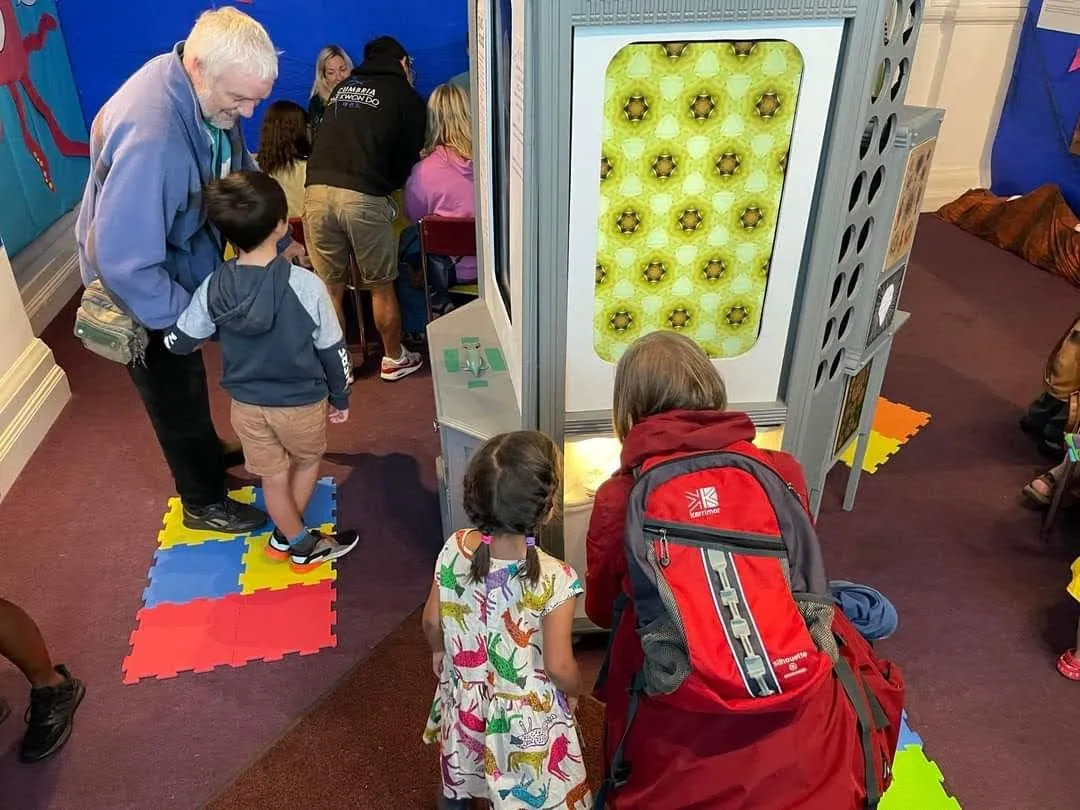 Crouching Woman and young girl looking at a screen showing a kaleidoscope 