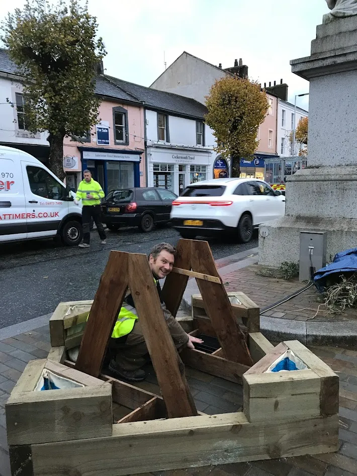 Man crouched inside a low wooden structure