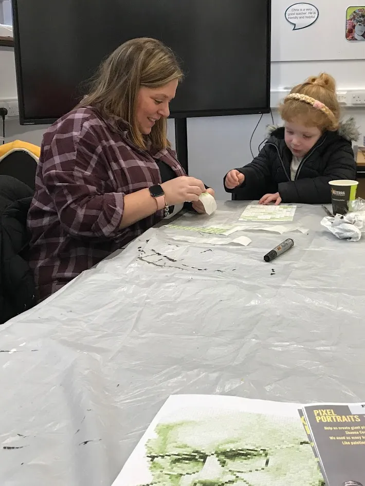 Woman and girl sitting putting on stickers