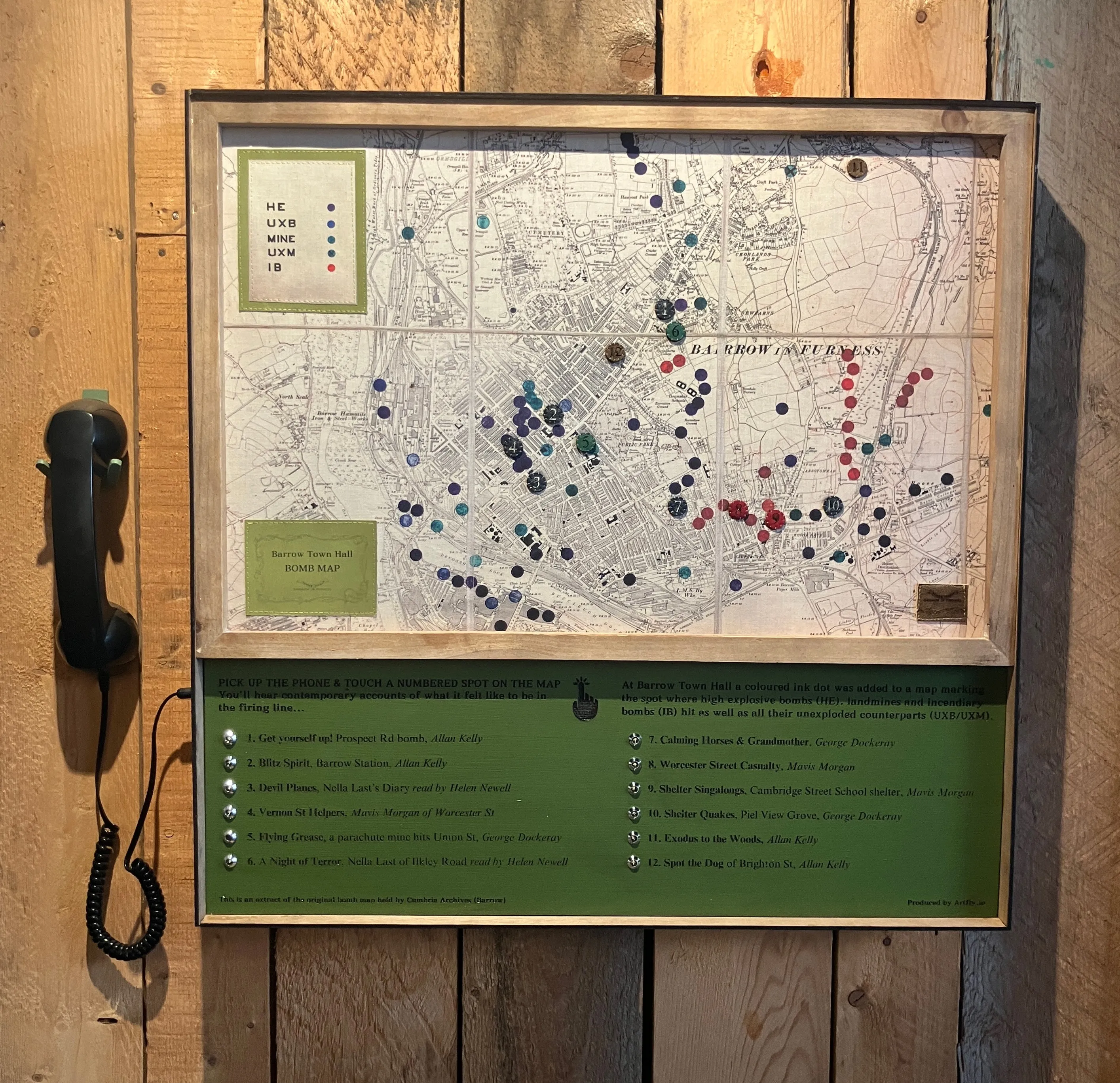 Map framed on a wooden wall with a phone plugged into it.