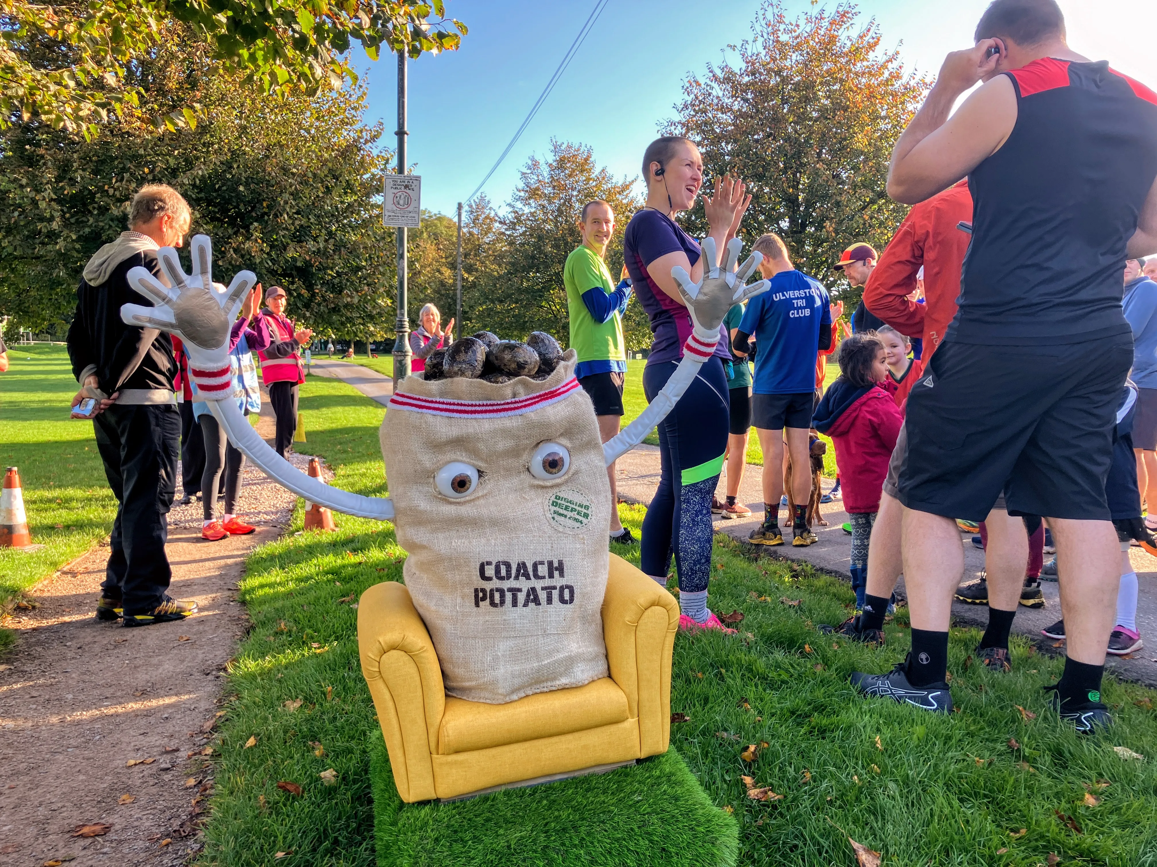Potato sack with arms raised amoung runners at a park