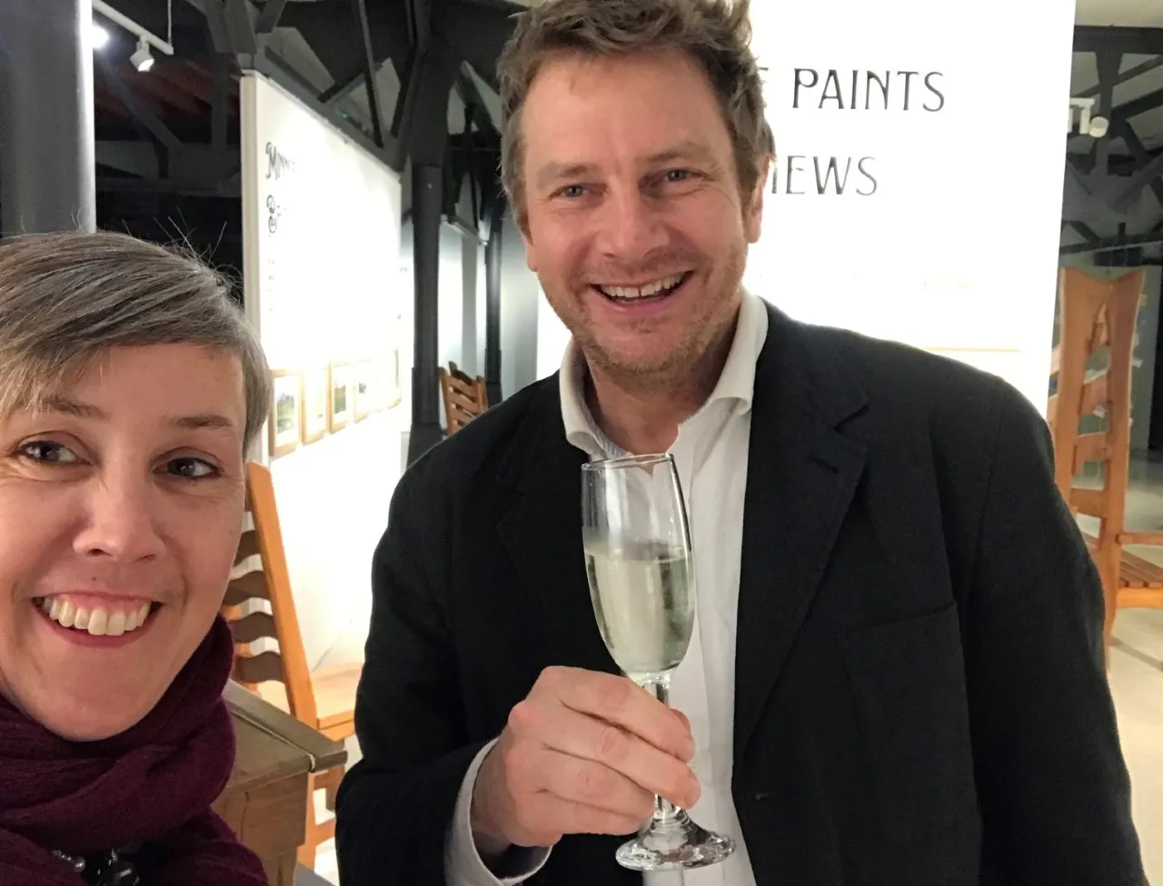 Man and woman smiling. The man is holding a glass of champagne.