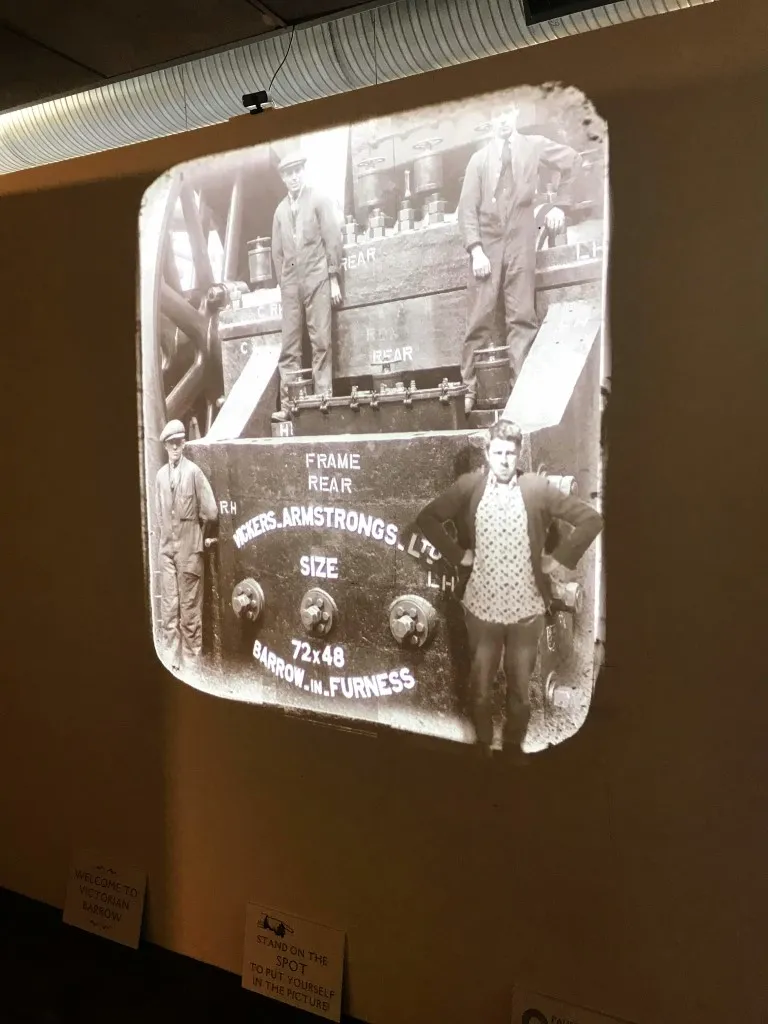 projected view of men standing on large metal machinery.