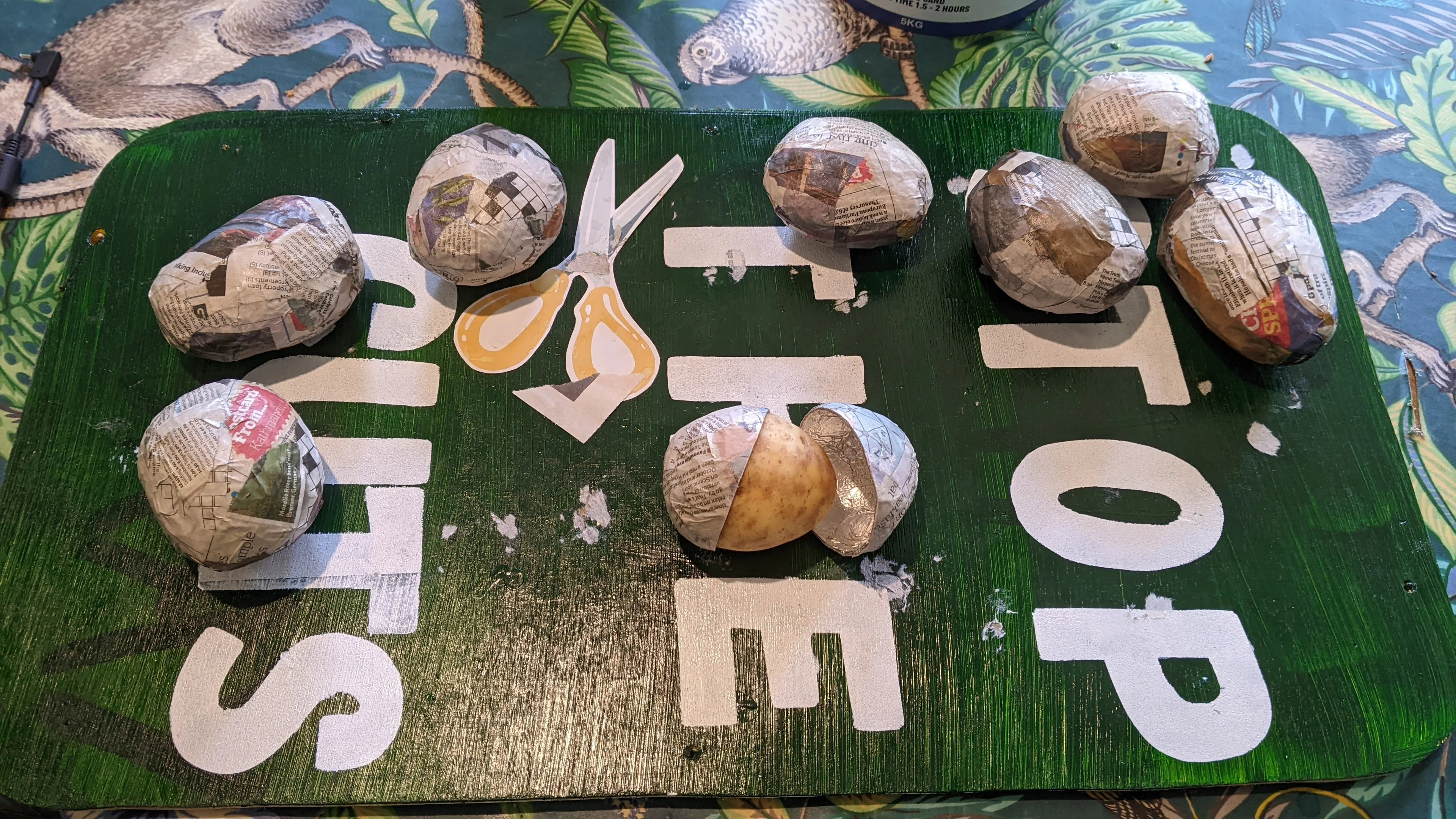 Potatoes covered in newspaper on a board saying Stop the Cuts