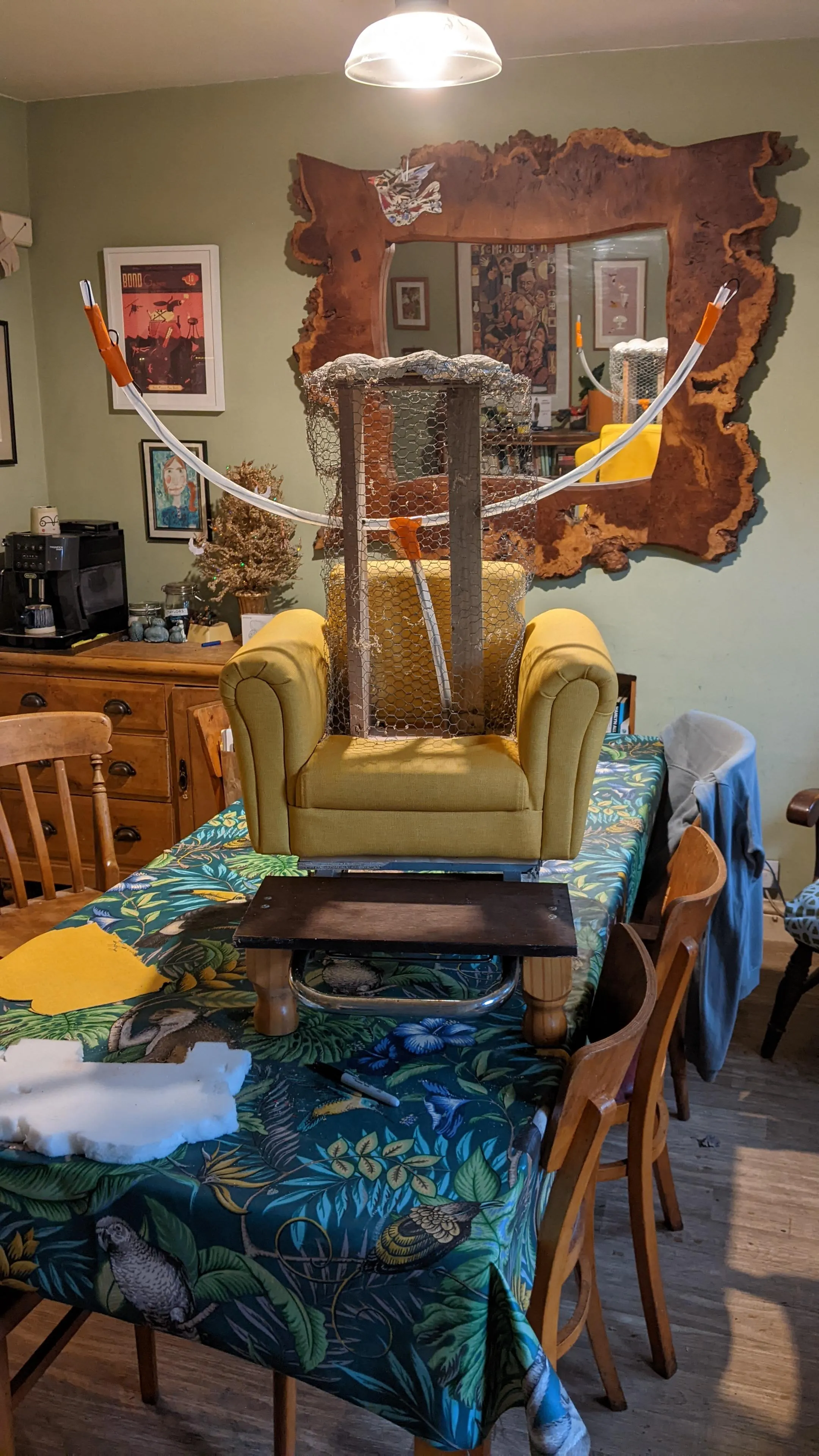 partially constructed project on a table. small arm chair with wooded posts, chicken wire and
clear pipes protruding from it