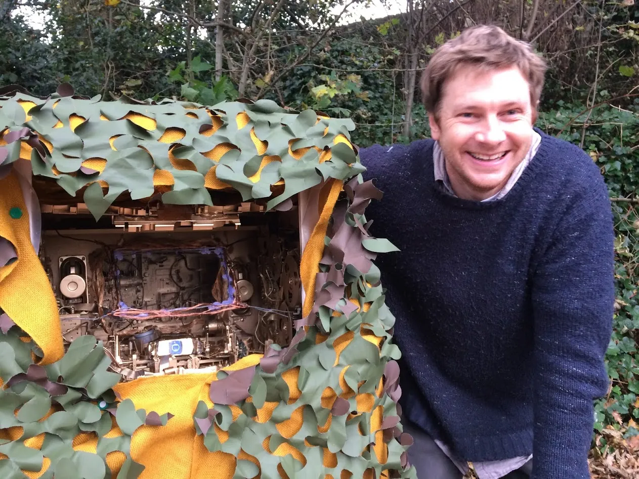 Man next to box with hole in the front showing electronics.