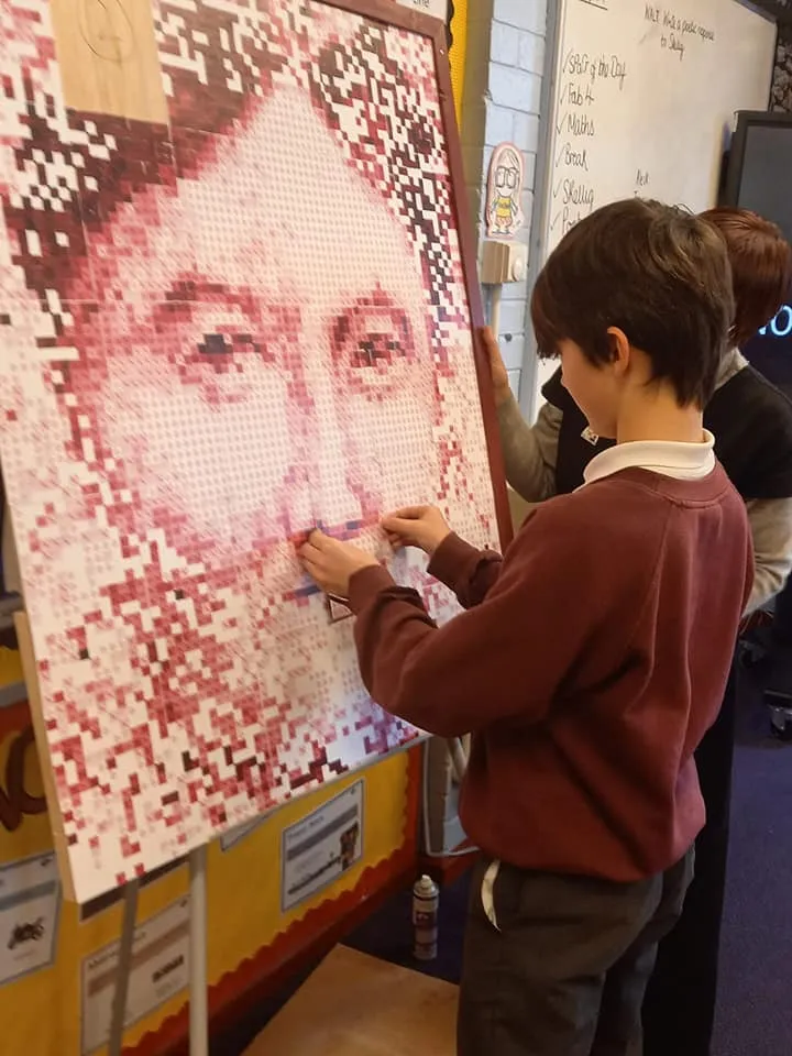 Child sticking a card to a board to complete the picture of Dorothy