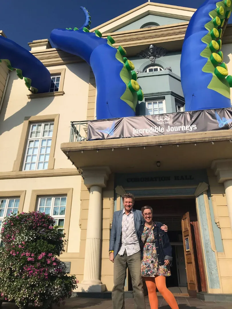 A man and woman standing outside a building with giant inflatable tentacles