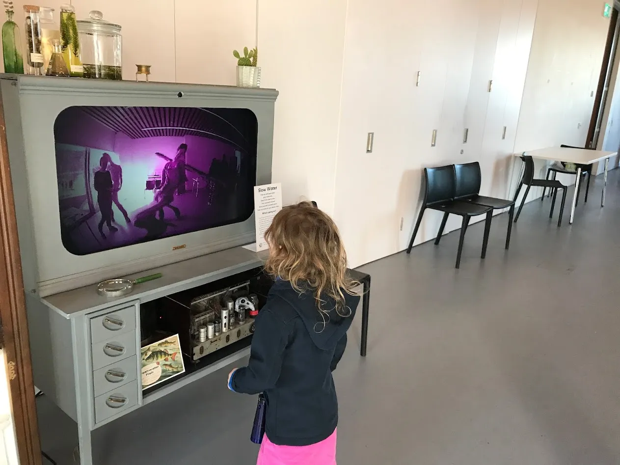 Girl looking into distorted picture on screen.