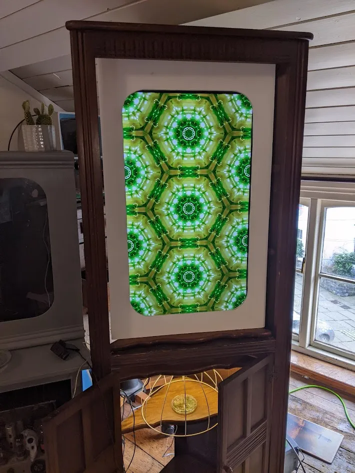 Kaleidoscope image on a tv screen above a petri dish of weed.