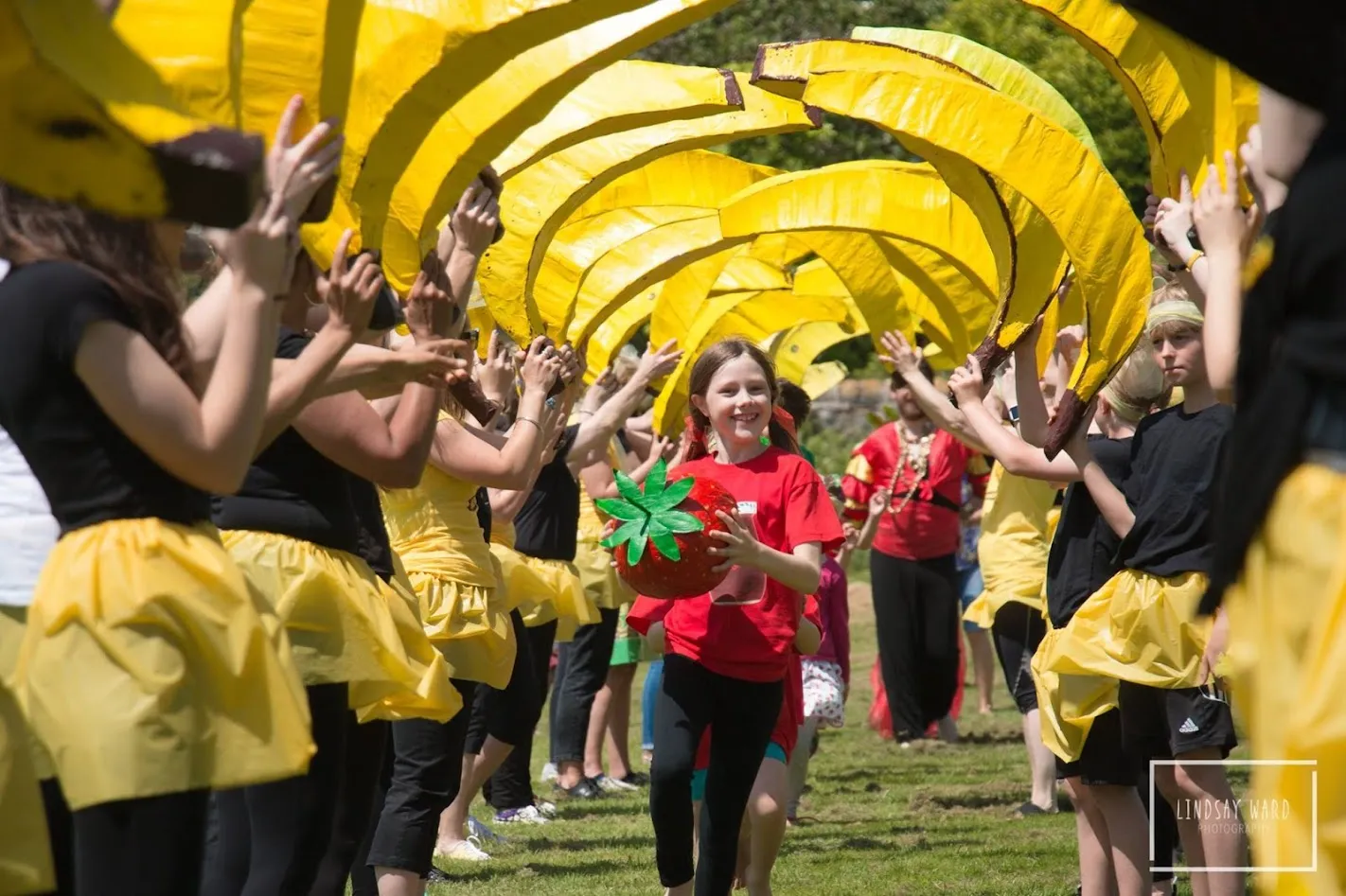 girl holding strawberry dancing up a line of bananas.