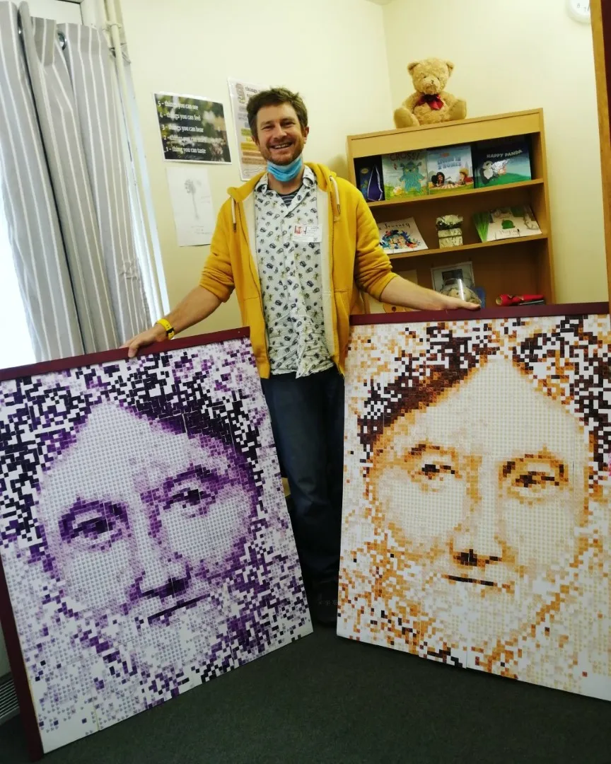 Chris standing by two completed pixel protraits