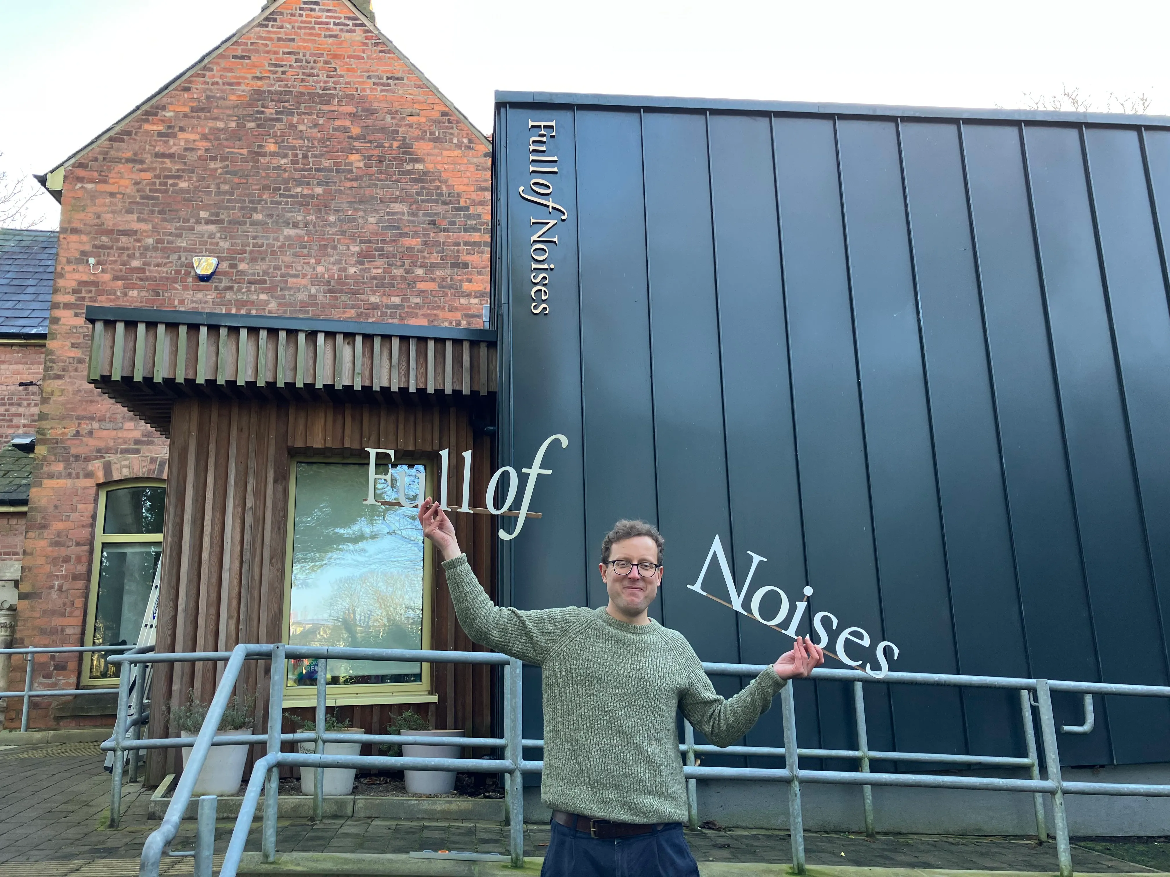 man holding up letters spelling 'Full of' in one hand and 'Noises' in the
other