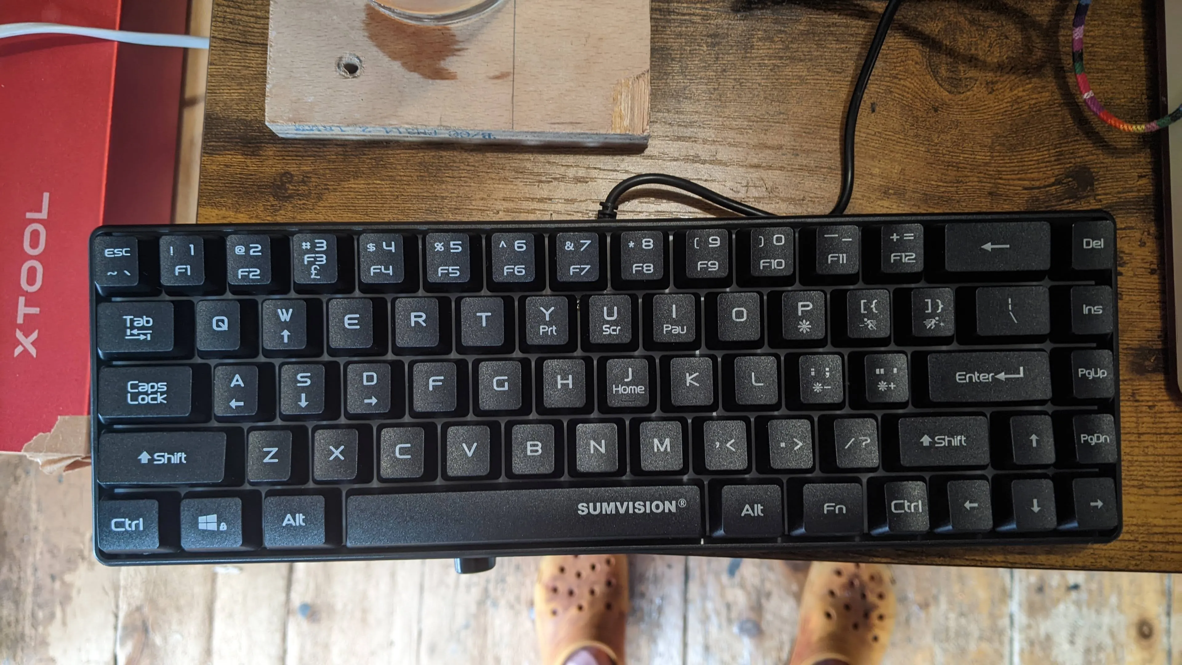 computer keyboard on desk with feet beneath