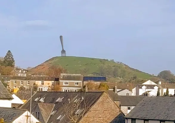 A drawing of a giant table fork stuck in a hill