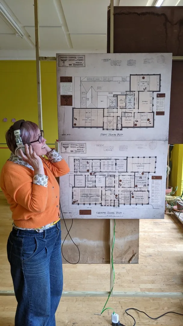 woman wearing headphones standing next to a picture