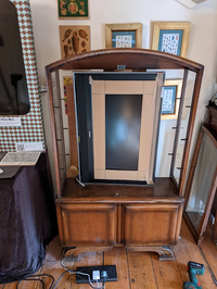 Display cabinet with doors taken off with tv on its side inside.