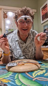 man holding soldering iron with magnifying lens glasses
