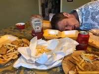 man asleep amongst chips and beer cans