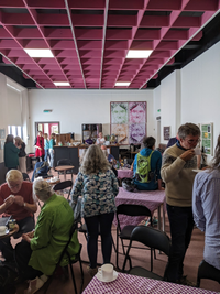 Group of people around tables with large picture on the wall at the back