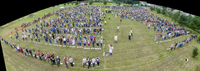 Bird's eye view of field with over 1000 people standing in lines next to pies